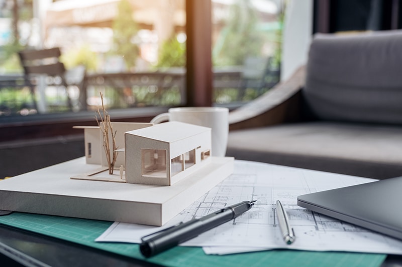 An architects designed architecture model with shop drawing paper and laptop on table